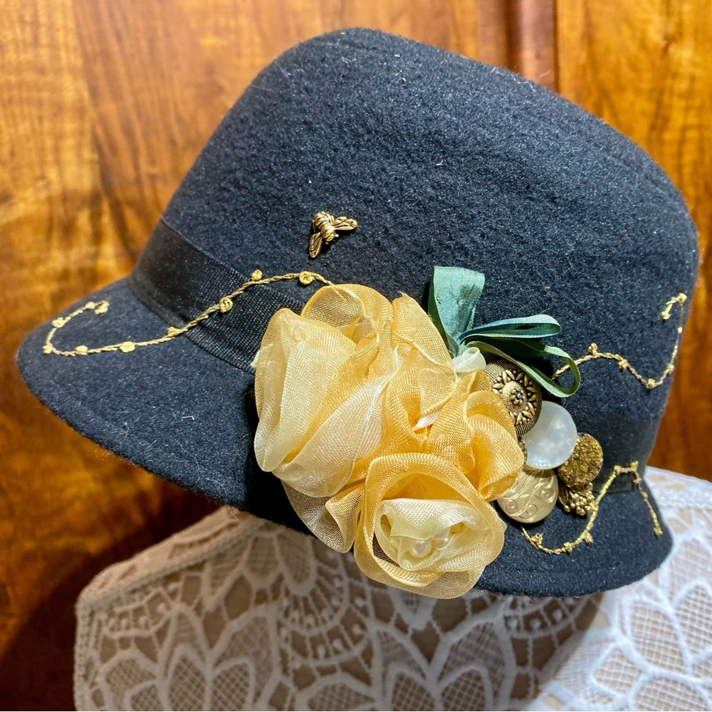Black Cloche style hat with handmade roses, gold trim work, a bee and buttons